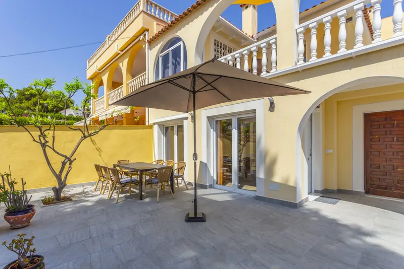 Esstisch mit Sonnenschirm auf der Terrasse vor der Villa